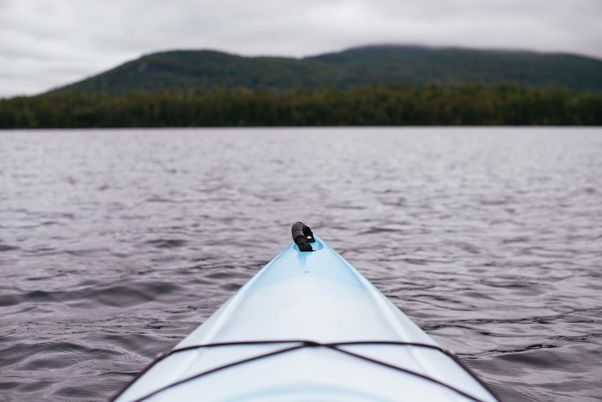 Kayak in a lake with a forest and a mountain in a blurred background